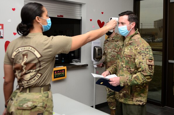 Senior Airman Mariah Harris, 44th Aerospace Medicine Squadron commanders support staff, takes the temperature of Maj. Ryan Armstrong, 89th Airlift Squadron C-17 pilot, before he signs in to get his Moderna COVID-19 vaccine Feb. 26, 2021, Wright Patterson Air Force Base, Ohio. To prevent the spread of COVID-19, Airmen were given staggered time slots and maintained physical distancing per Centers for Disease, Control and Prevention guidelines. (U.S. Air Force photo/Mr. Darrell Sydnor)