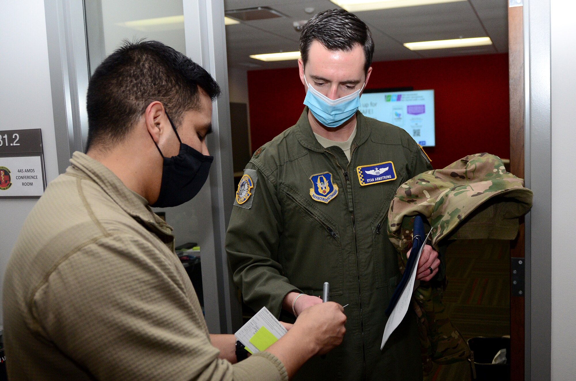 Master Sgt. Christian De La Cruz, 445th Aerospace Medicine Squadron aerospace medical technician, gives Maj. Ryan Armstrong, 89th Airlift Squadron C-17 pilot, a COVID-19 vaccination record card Feb. 26, 2021. De La Cruz also provided a sticky note with the time the vaccine was administered for evaluation purposes. AMDS staff members monitored each Airman for development of side effects. The two-dose vaccine was recently approved by the Food and Drug Administration under an emergency use authorization and are currently offered to Defense Department personnel on a voluntary basis. (U.S. Air Force photo/Mr. Darrell Sydnor)