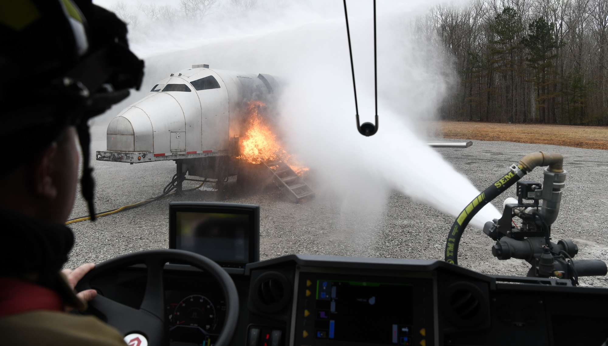 An Arnold Air Force Base Fire and Emergency Services firefighter operates a vehicle mounted nozzle from the cab of the vehicle, Feb. 9, 2021, while training on aircraft rescue and firefighting techniques using a propane-fueled trainer brought to the base. Firefighters trained on battling blazes both with vehicle-mounted nozzles and hand lines. (U.S. Air Force photo by Jill Pickett)