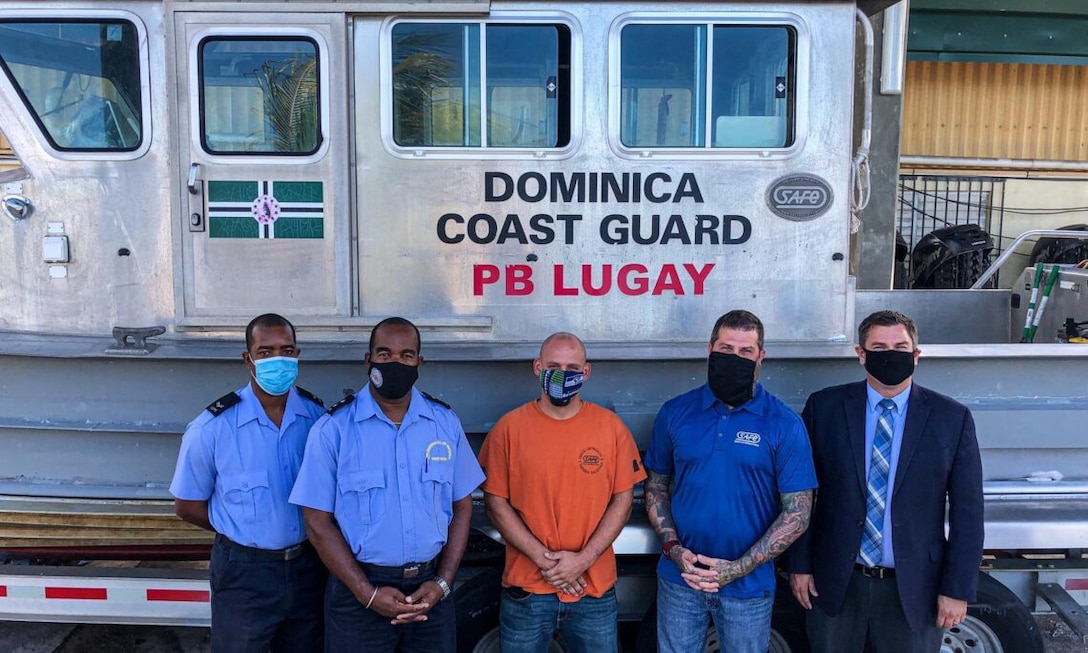 U.S. and Dominican personnel stand in front of a Dominica Marine Unit vessel.