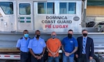 U.S. and Dominican personnel stand in front of a Dominica Marine Unit vessel.