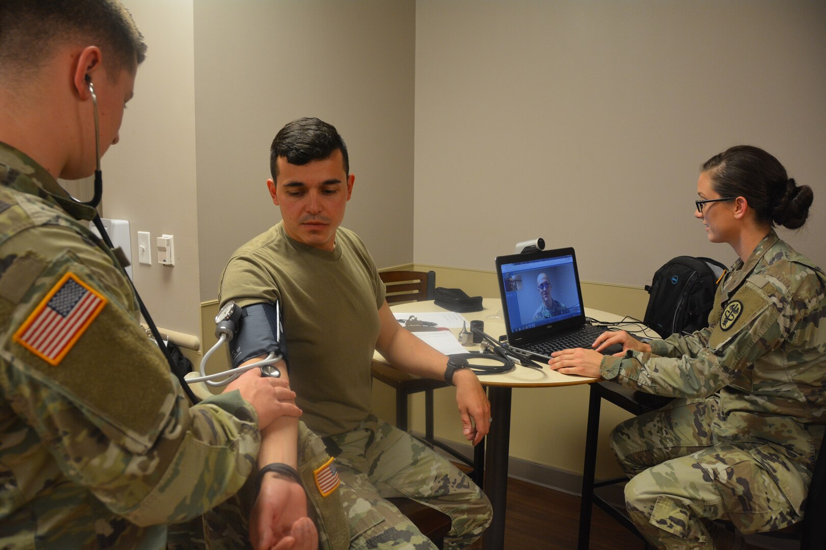 Mobile Medic Spc. Amanda Knight sets up a video chat with a medical provider while Mobile Medic Spc. Joshua Rath checks Spc. Joao Dos Santos Faustino's vitals during an early morning sick call at the 232nd Medical Battalion Sept. 25 2017.