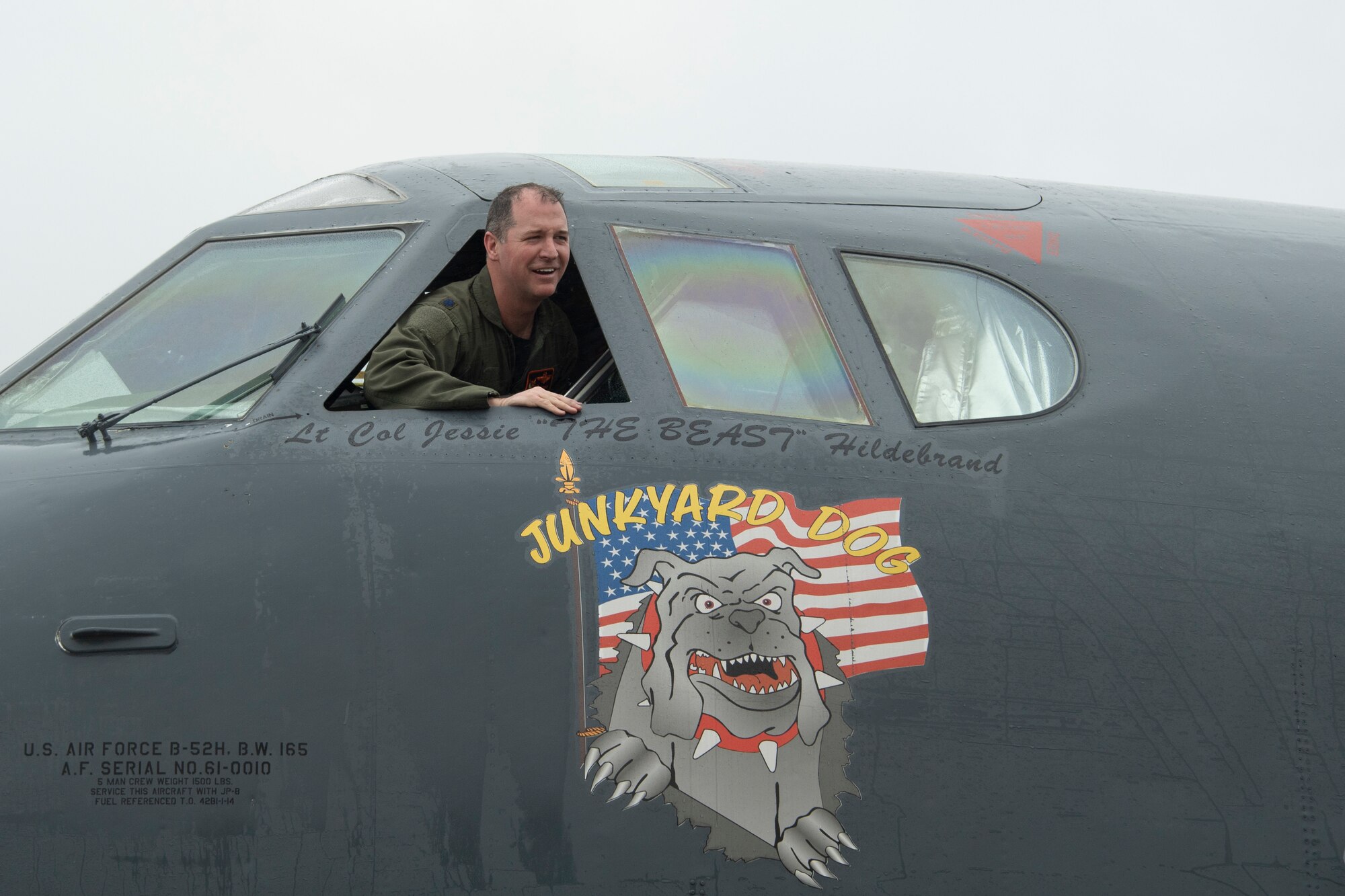 An Airman sticks his head out of the cockpit of a B-52 and smiles.