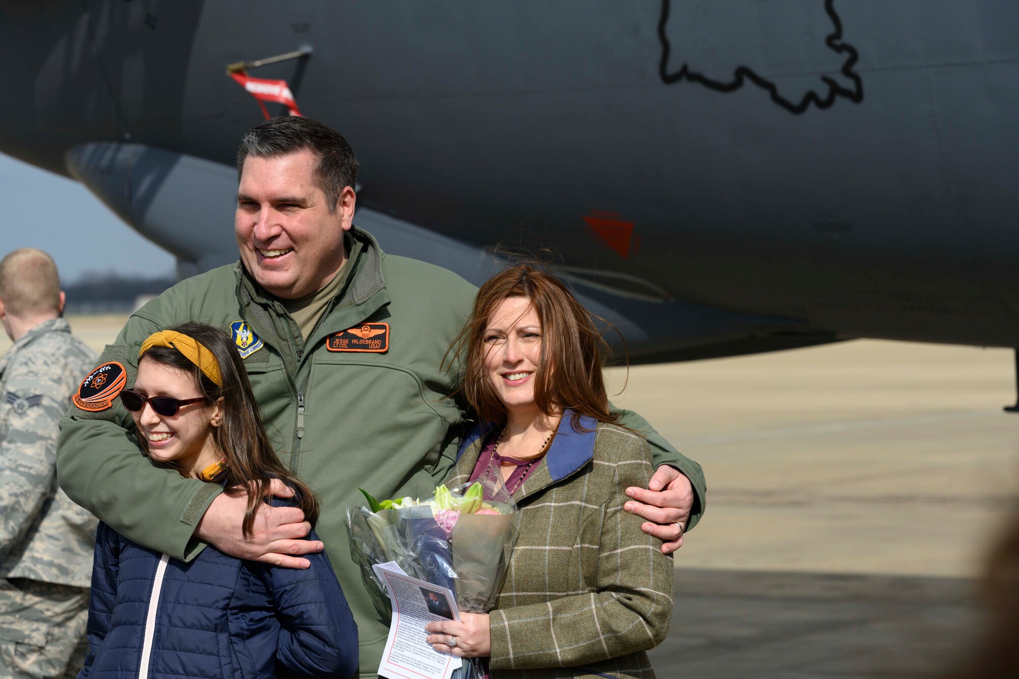An Airman stands with his family outside a jet.