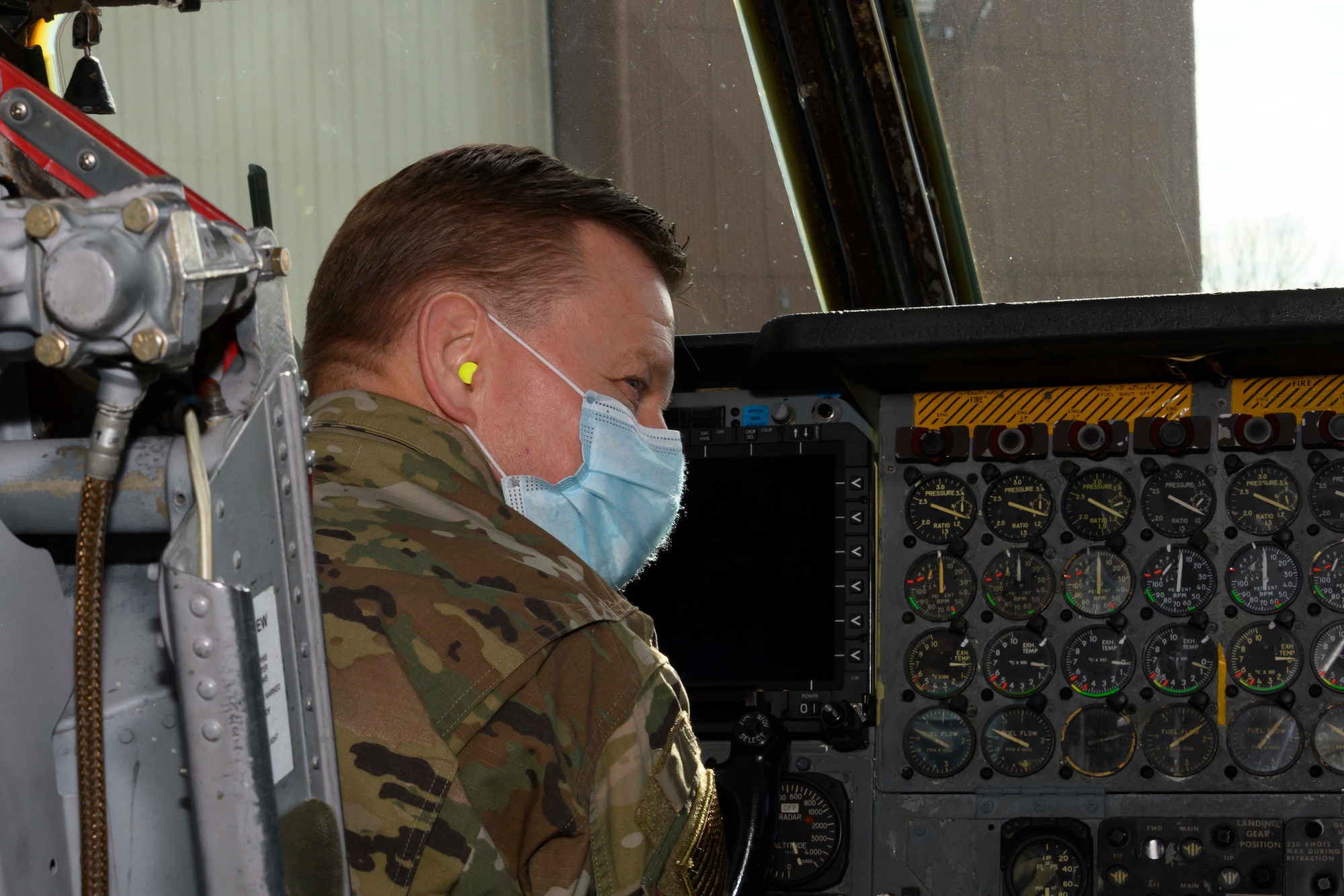 An Airman wearing a mask looks at a B-52 cockpit.