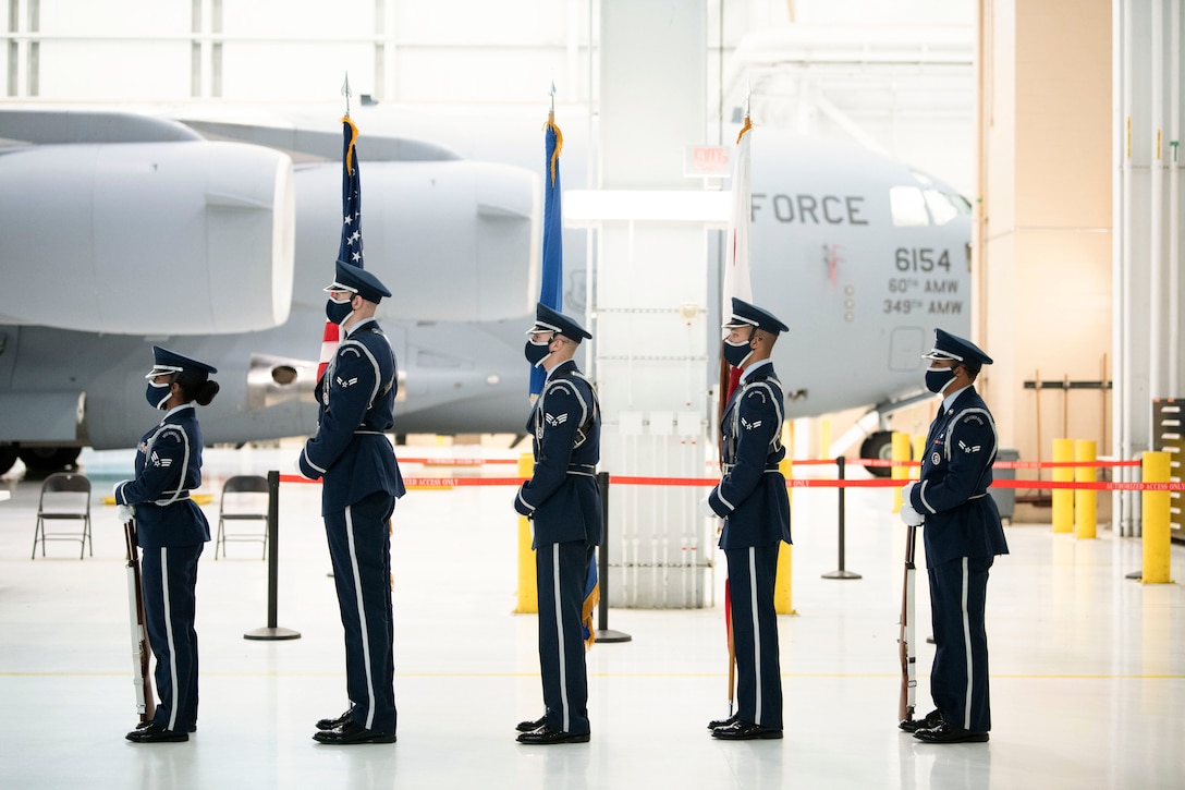 Airmen present colors with aircraft in the background.
