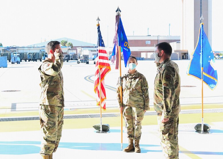 Two uniformed personnel salute each other during ceremony