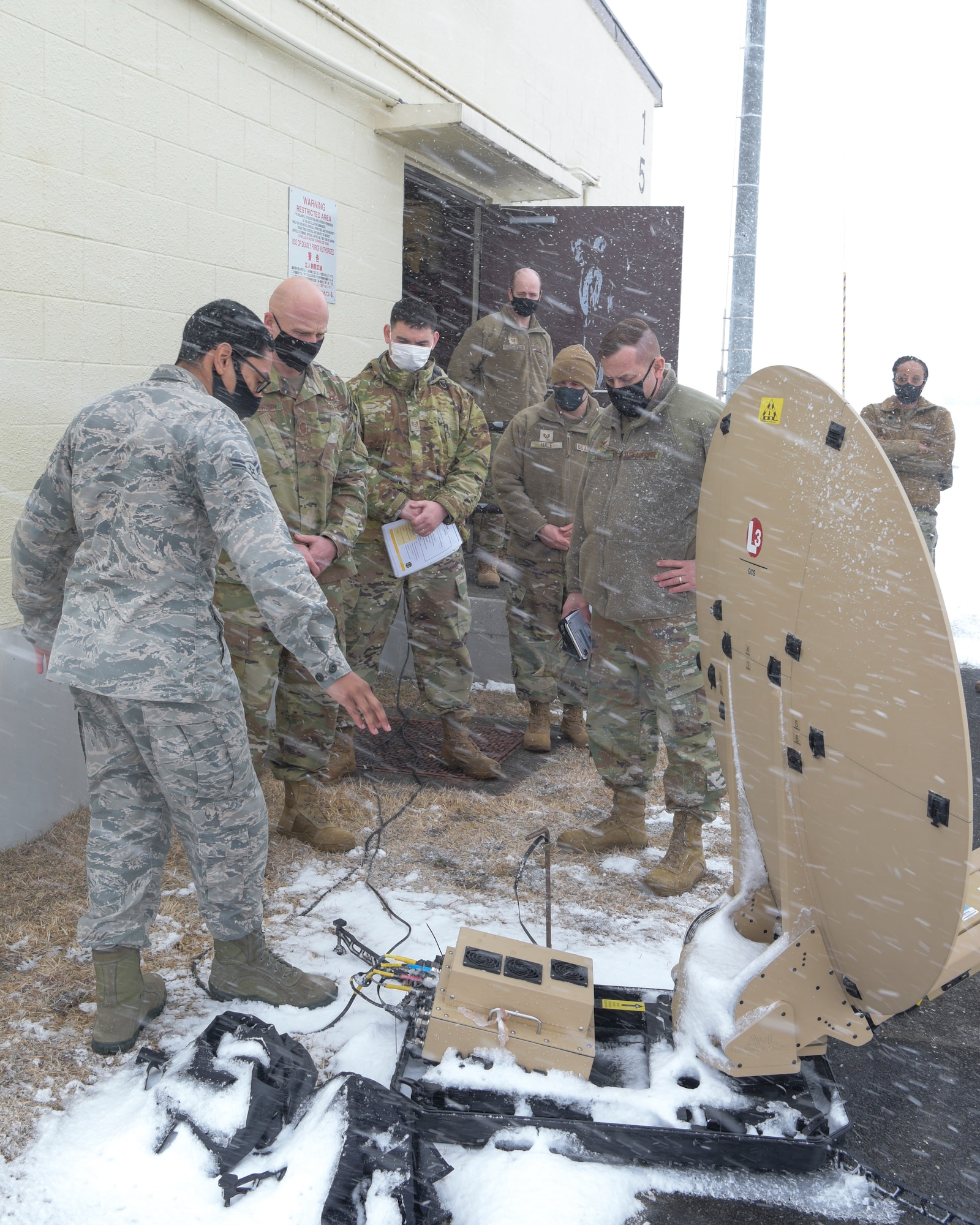 U.S. Air Force Airman 1st Class Lathaniel Labrador, left, a 35th Communications Squadron radio frequency transmission system technician, presents a deployable satellite communications antenna to Col. Jesse J. Friedel, the 35th Fighter Wing commander, and Chief Master Sgt. Joey R. Meininger, the 35th Fighter Wing command chief, during a Wild Weasel Walk-Through at Misawa Air Base, Japan, Feb. 23, 2021.