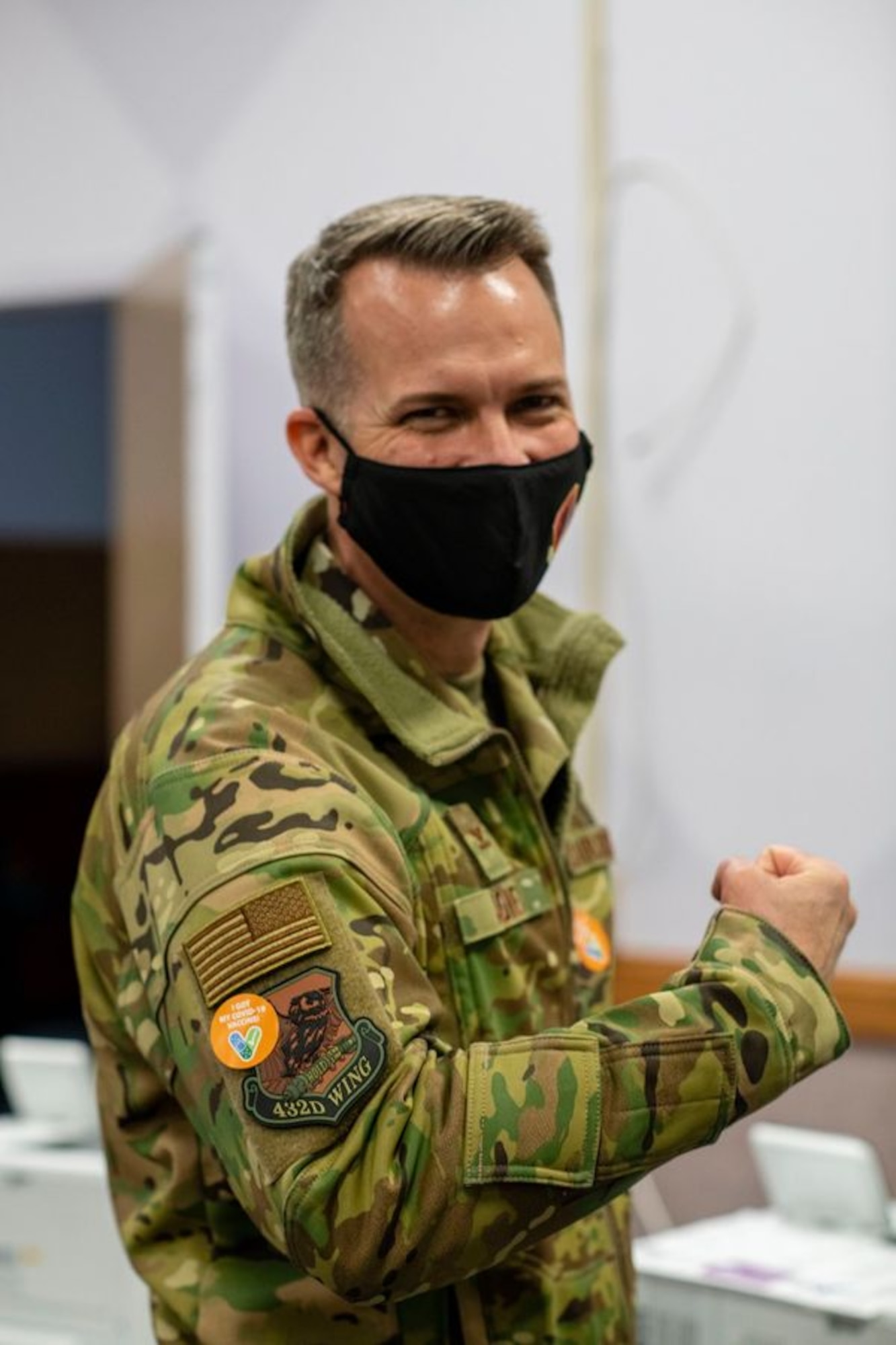 Col. Stephen R. Jones, 432nd Wing/432nd Air Expeditionary Wing commander, flexes his arm showing off his "I got vaccinated" sticker on his wing patch.