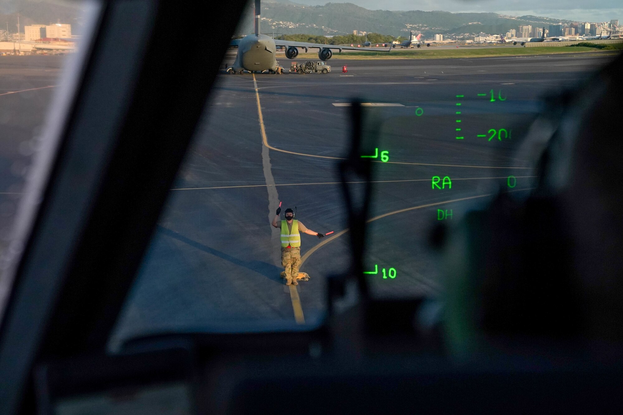 A Civil Air Patrol cadet marshals a C-17 Globemaster III after a training mission over Maui, at the Kahului Airport, Hawaii, Jan. 31, 2021. Aircraft marshals assist pilots by helping direct and park the aircraft after a flight due to the limited visibility between the aircraft and the ground from the cockpit.  (Air Force photo by Airman 1st Class Makensie Cooper)