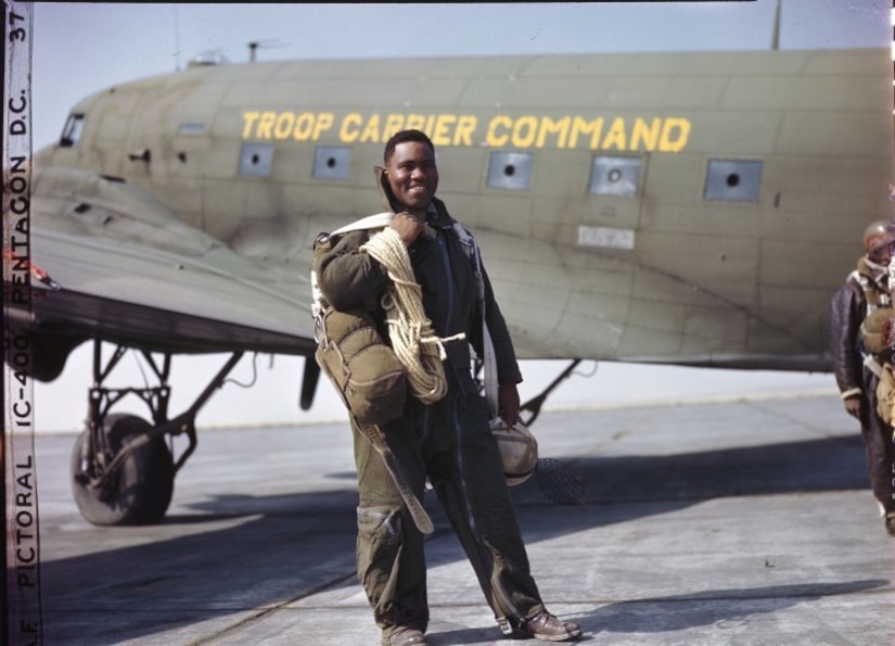 Army Lt. Clifford Allen of Chicago, Illinois, is one of the fire fighters of the all-black 555th Parachute Infantry Battalion. He wears his complete outfit just before taking off for a jump. Note the 150 ft. rope descending from tall trees; the plastic helmet and catcher’s mask are protections against branches and brambles. Known as the Triple Nickles, the 555th completed 1200 jumps from July-October 1945 in support of the U.S. Forest Service efforts to contain forest fires in the northwest United States. The smokejumpers parachuted into regions difficult for firefighters to reach and helped contain 36 fires during this time.