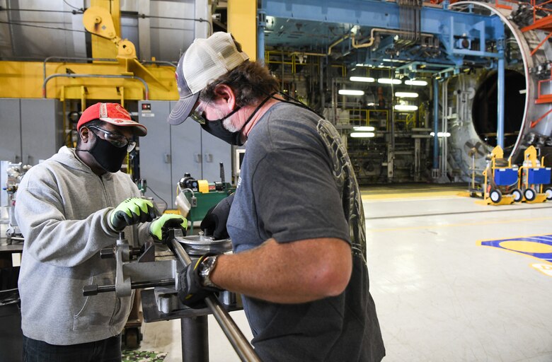 Machinists Will Burnette, left, and Matt Henley bend a pipe, Oct. 15, 2020, while working in the C Plant of the Engine Test Facility at Arnold Air Force Base, Tenn. Behind the machinists on the right is the C-1 test cell. (U.S. Air Force photo by Jill Pickett)