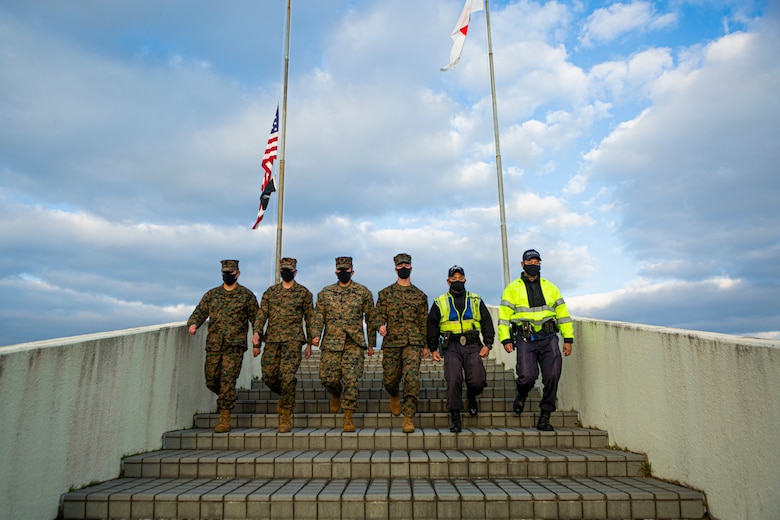 U.S. Marines and Japanese Security Guards march down stairs after a colors ceremony on Camp Foster, Okinawa, Japan, Jan. 13, 2021. Performing a daily colors ceremony with the host nation symbolizes the cooperation and joint effort of American and Japanese forces throughout Japan. . (U.S. Marine Corps Photo by Cpl. Christopher A. Madero)