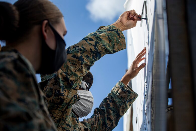 U.S. Marine Corps Lance Cpl. Jazlynn Newcomb, a commercial clerk with the Distribution Management Office, and Lance Cpl. Michael Hendricks, a postal clerk with the Camp Foster Post Office, mark a target signifying where a Marine has shot on Camp Schwab, Okinawa, Japan, Feb. 2, 2020. Once a year, Marines are required to shoot on the known distance course of fire, tables one and two. Upon completion, Marines are awarded a score of marksmanship, sharpshooter or expert. Newcomb is a native of South Paris, Maine and Hendricks is a native of Brooklyn, New York. (U.S. Marine Corps photo by Cpl. Karis Mattingly)