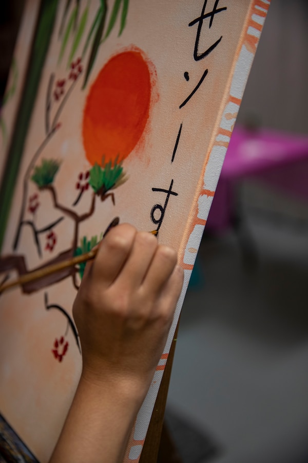 Marines sign their paintings in Hiragana during a Single Marine Program (SMP) paint and pizza event at Camp Foster, Okinawa, Japan, Jan. 10, 2021. The SMP strives to help single and unaccompanied Marines by hosting recreation and volunteer events. (U.S. Marine Corps photo by Lance Cpl. Zachary Larsen)