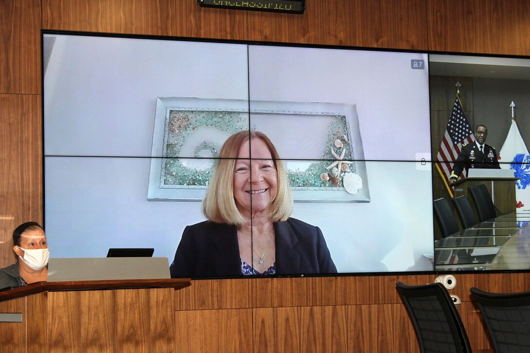 A woman celebrates her retirement remotely via a virtual screen.