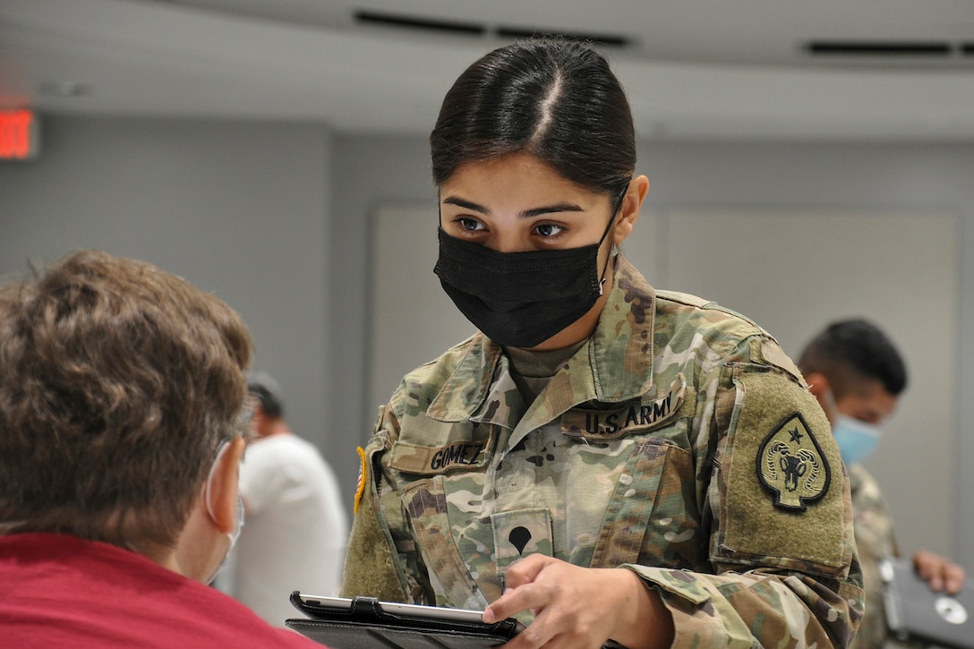 A soldier wearing a mask speaks to a civilian.