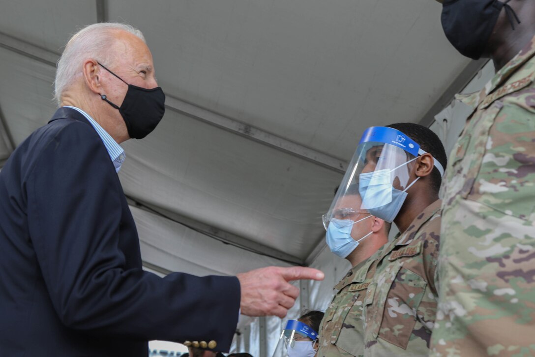 President Joe Biden talks with airmen in a covered outdoor space