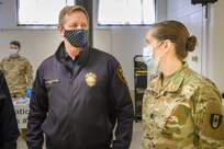 U.S. Army Lt. Col. Sally DelVecchio, a pulmonary critical care physician, from 531st Hospital Center, and Ron Van Kluyve, Deputy Police Chief of Paterson Police Department, discuss the vaccination process and procedures at the state-run, federally-supported COVID-19 Community Vaccination Center in Paterson, New Jersey, March 1, 2021.