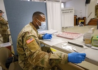 U.S. Army Spc. Daniel Mickson, a practical nursing specialist from 531st Hospital Center, provides vaccination information to a community member at the state-run, federally-supported COVID-19 Community Vaccination Center in Paterson, New Jersey, March 1, 2021.