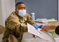 U.S. Army Spc. Daniel Mickson, a practical nursing specialist, from 531st Hospital Center, provides vaccination information to a community member  at the state-run, federally-supported COVID-19 Community Vaccination Center in Paterson, New Jersey, March  1, 2021.
