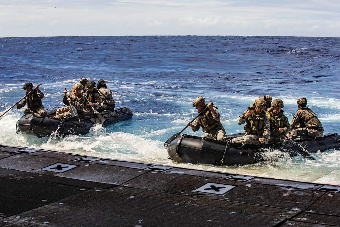 Marines offload in combat rubber raiding crafts from a ship at sea.