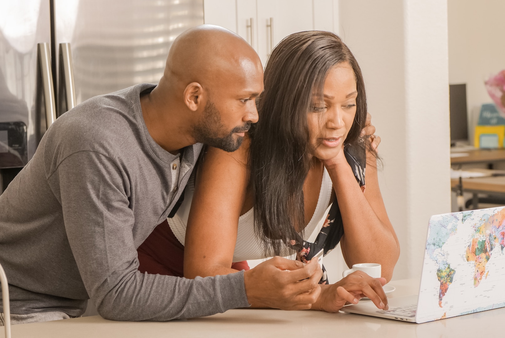 A man and woman look at open laptop