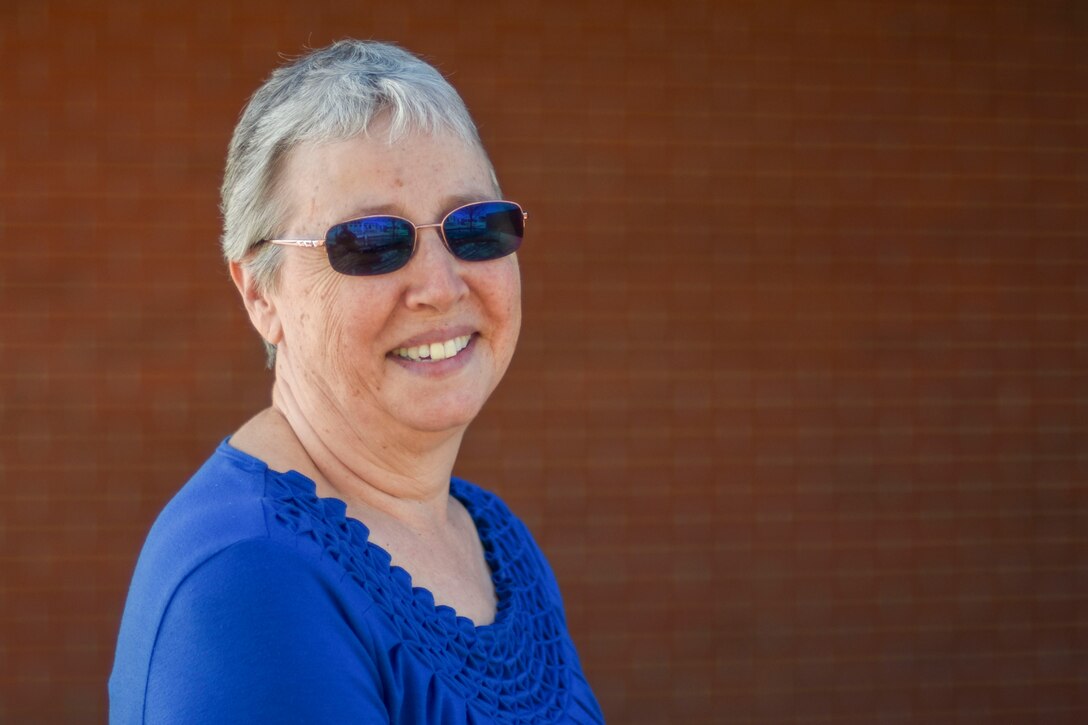 Carol Ameline poses next to a wall.