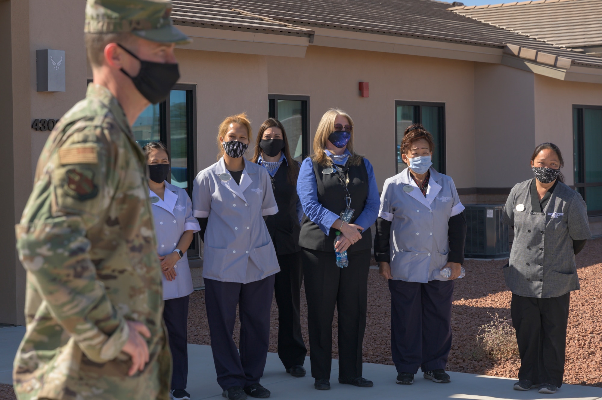 People stand in front of a building and cut a ribbon