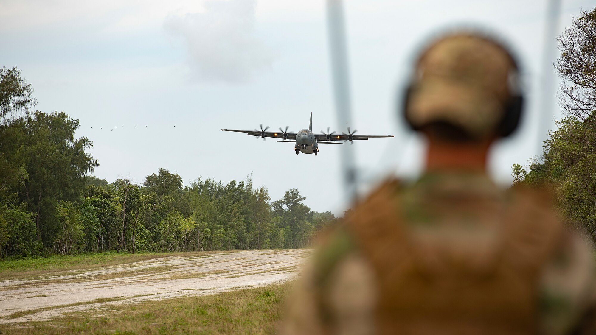 U.S. Air Force Capt. Gene Walker, 36th Contingency Response Squadron assistant director of operations, watches a C-130J Super Hercules from Yokota Air Base approach the landing zone during Cope North 21, Feb. 11, 2021, on Angaur, Palau.