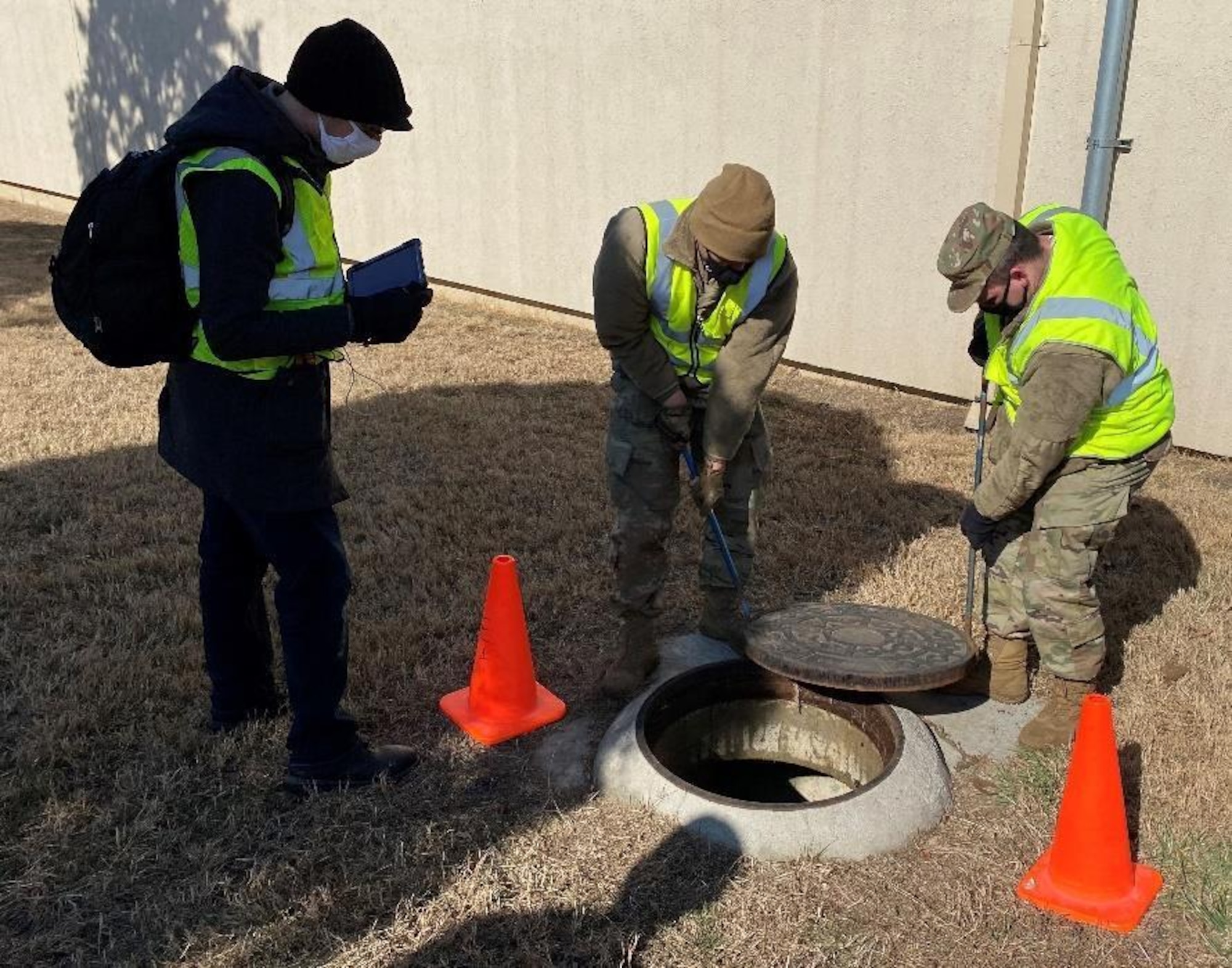 Airmen install a manhole cover.