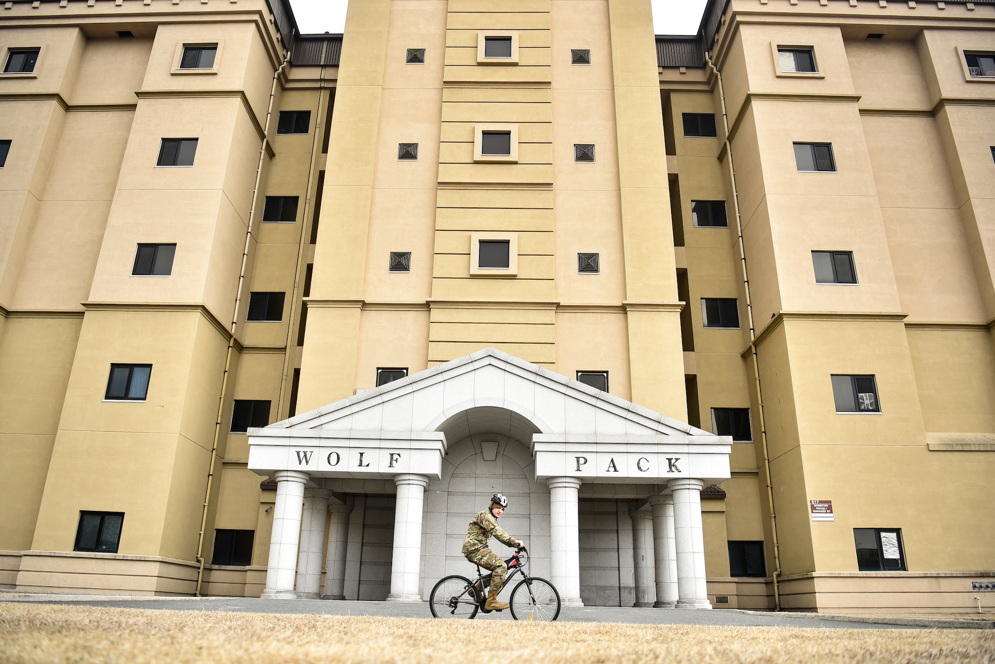 An Airman cycles by a building.