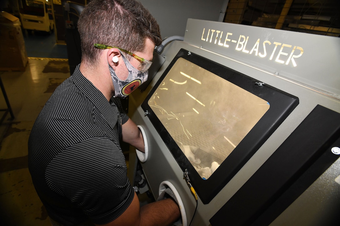 Fleet Readiness Center Southeast (FRCSE) mechanical engineer, Evan Grambling, utilizes a manual glass bead blaster as part of the processing procedures involved in the 3D printing of nasopharyngeal swabs.