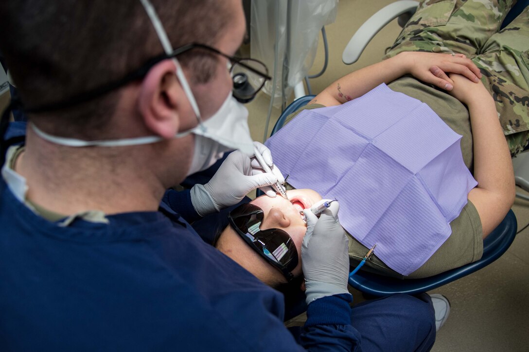 Maj. James Koll, 22nd Operational Medical Readiness Squadron dental flight commander, cleans and inspects the teeth of Airman 1st Class Marissa Kruse, 22nd Aircraft Maintenance Squadron crew chief, Mar. 1, 2021, at McConnell Air Force Base, Kansas. The dental clinics mission is to ensure the dental readiness and oral health of all patients, which allows them to deploy and carry on the aerial refueling mission at a moment’s notice. (U.S. Air Force photo by Senior Airman Alexi Bosarge)