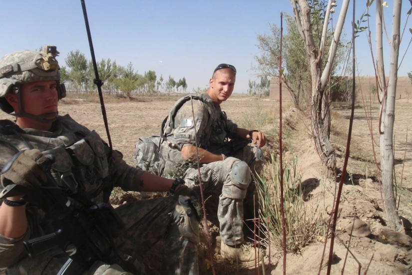 Two soldiers sit on the ground.