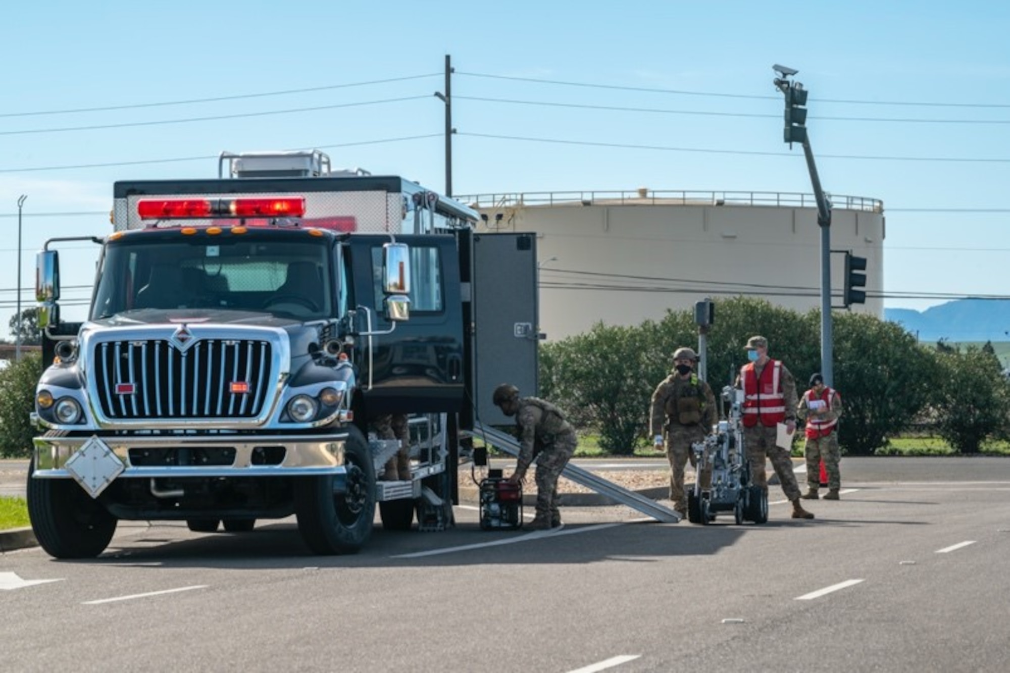 Airmen in bright vests unload a bomb-defusing robot from a truck