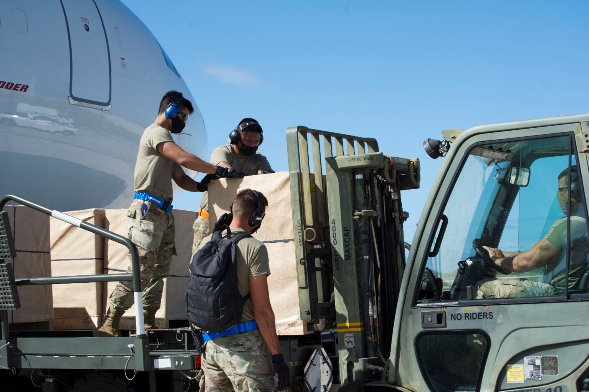 A team of Reserve Citizen Airmen from the 44th Aerial Port Squadron guide COVID-19 reefers onto a forklift operated by the 734th Air Mobility Squadron member at Andersen Air Force Base, Guam, Feb. 23, 2021.