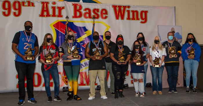 Airmen pose for a photo on stage holding awards.