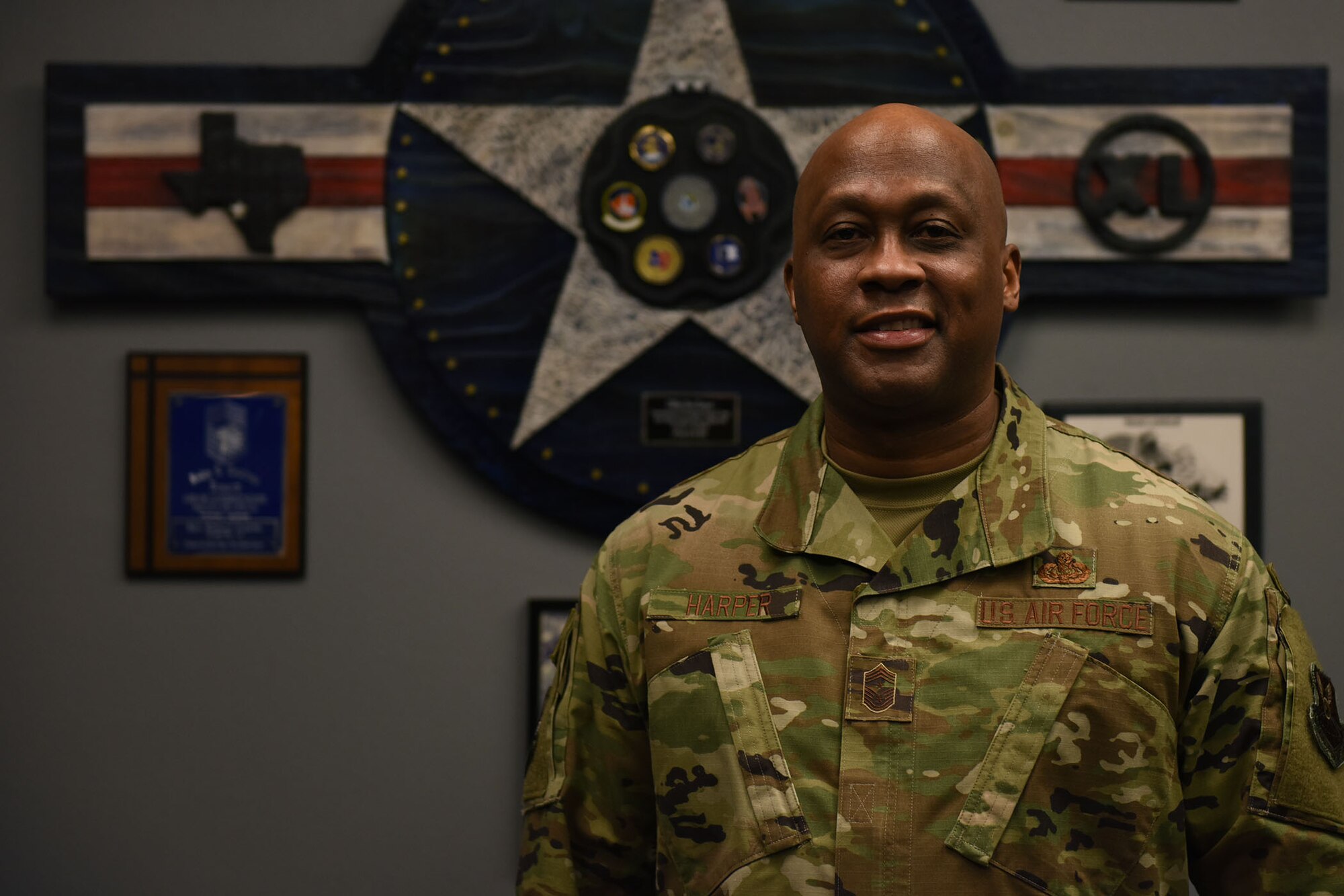 Chief Master Sgt. Ronald Harper poses for a portrait photo inside of his office, looks directly at the camera and smiles.