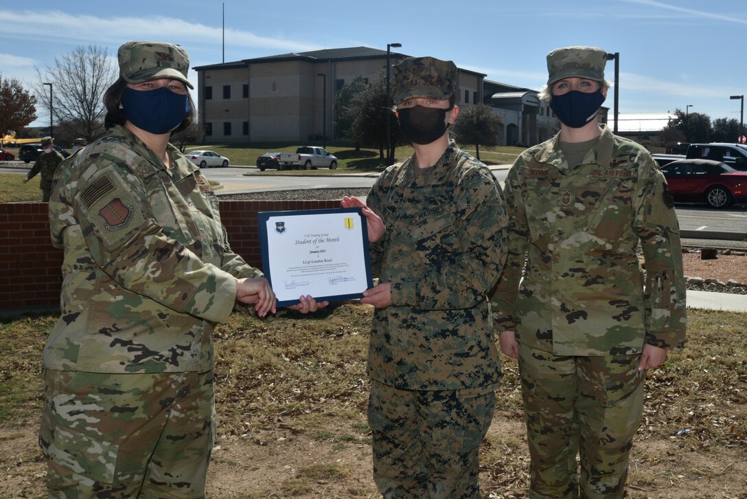 U.S. Air Force Col. Angelina Maguinness, 17th Training Group commander, presents U.S. Marine Lance Cpl. London Rizzi, 316th Training Squadron student, the 17th TRG Student of the Month award outside of Brandenburg Hall on Goodfellow Air Force Base, Texas, Feb. 26, 2021. The 316th TRS develops leaders and delivers relevant and realistic joint intelligence, surveillance and reconnaissance training for the Department of Defense. (U.S. Air Force photo by Senior Airman Ashley Thrash)