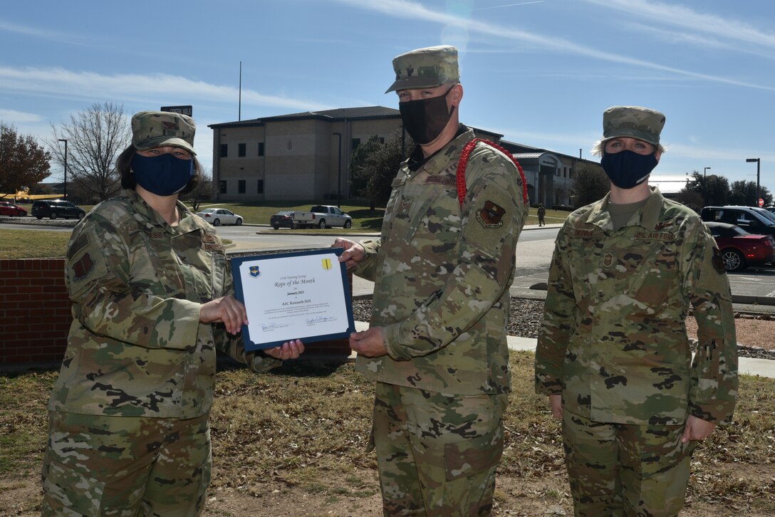 U.S. Air Force Col. Angelina Maguinness, 17th Training Group commander, presents Airman 1st Class Kenneth Hill, 312th Training Squadron student, the 17th TRG Rope of the Month award outside of Brandenburg Hall on Goodfellow Air Force Base, Texas, Feb. 26, 2021. The red rope is selected for showing exceptional leadership qualities and provides general supervision and guidance to the other students and ropes. (U.S. Air Force photo by Senior Airman Ashley Thrash)