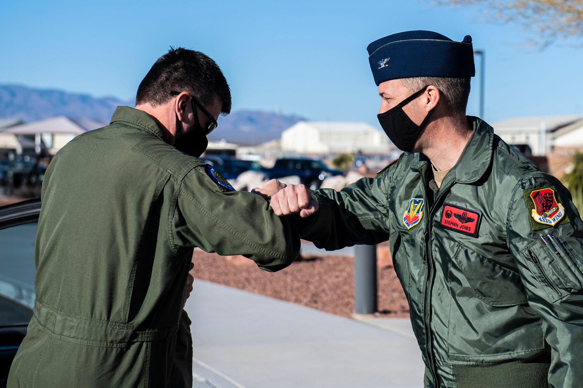 Two male Airmen elbow bumb outside.