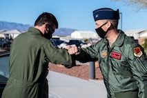 Two male Airmen elbow bumb outside.