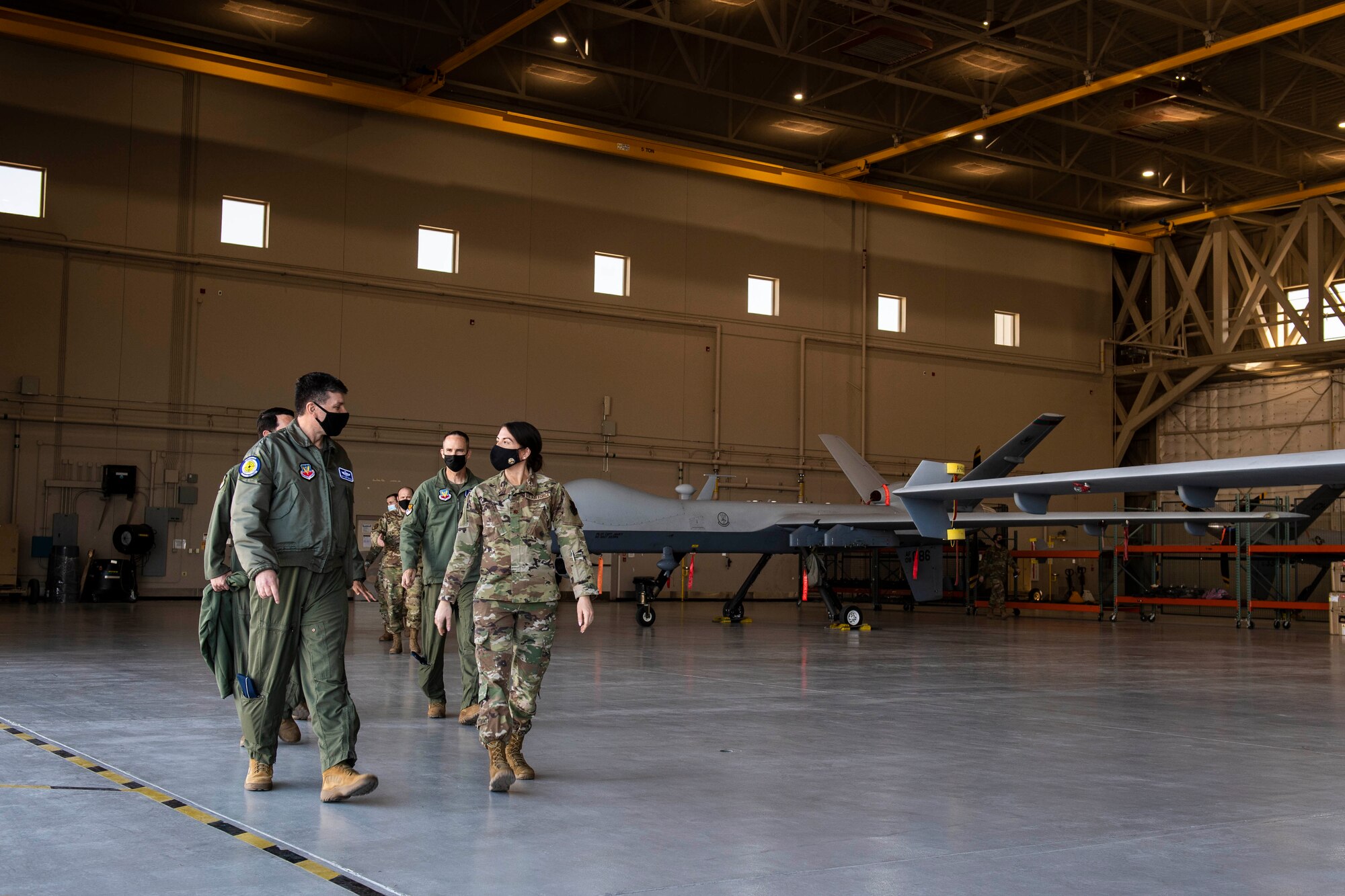 A group of Airmen walk toward the camera while talking to each other.