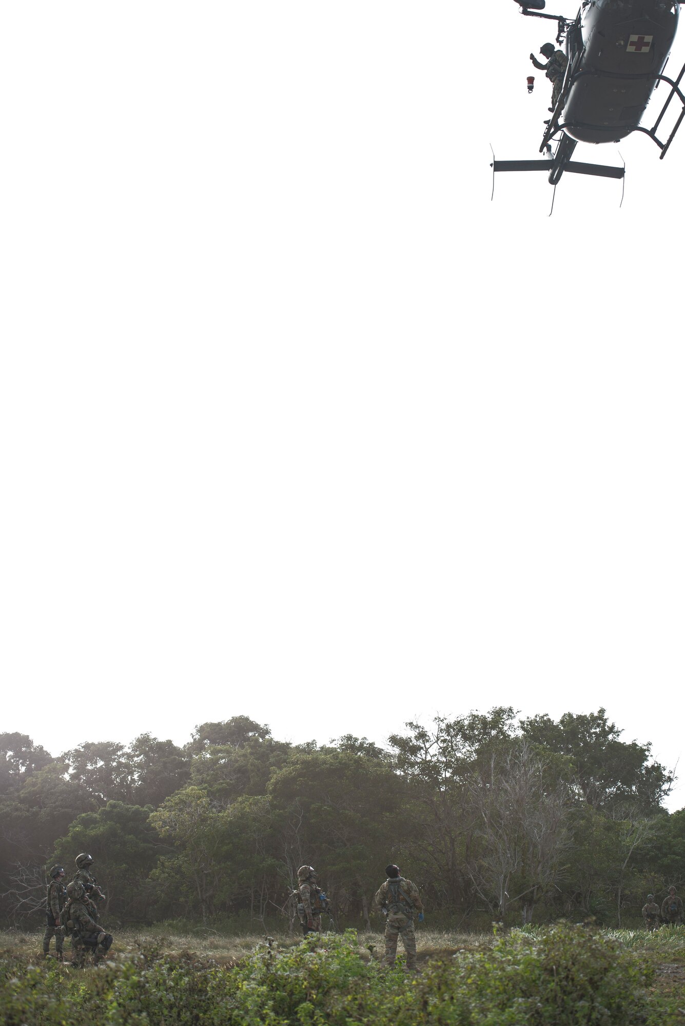 Multi-capable Airmen of the 644th Combat Communications Squadron wait as the cable is lowered from the Guam Army National Guard medical helicopter while training for emergency airlifts, during Exercise Dragon Shield at Northwest Field, Guam, January 13, 2021.