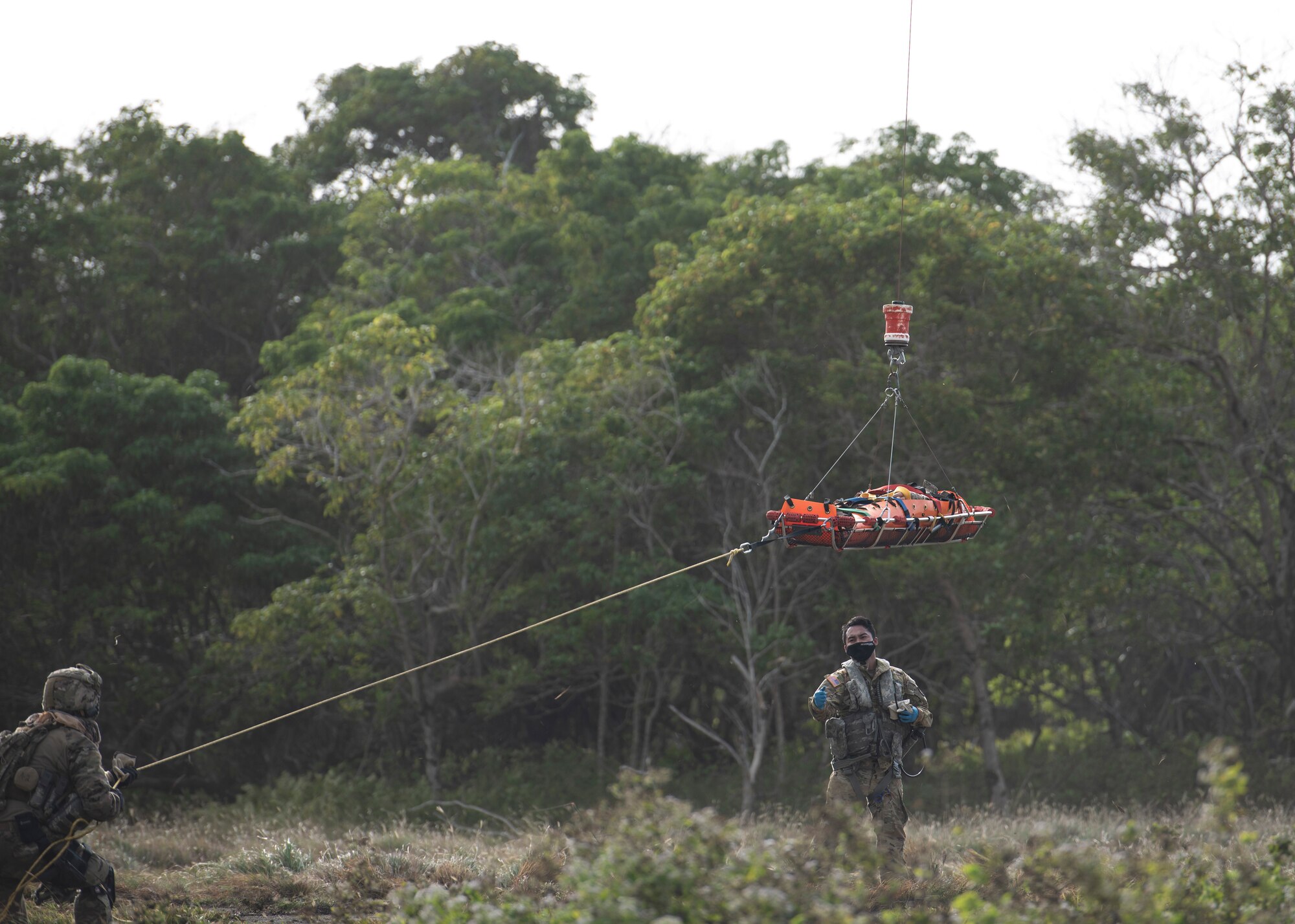 A U.S. Airmen of the 644th Combat Communications Squadron runs the trail line of the stretcher as it’s hoisted in to the Guam Army National Guard helicopter during Exercise Dragon Shield at Northwest Field, Guam, January 13, 2021.