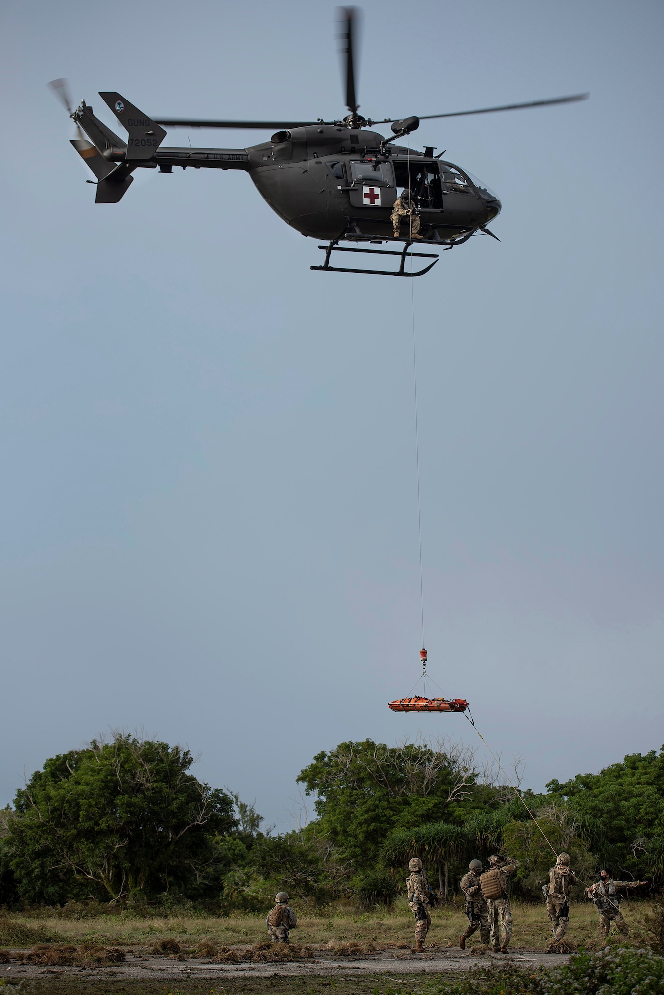 Multi-capable Airmen of the 644th Combat Communications Squadron run the trail line of the stretcher as it’s hoisted in to the Guam Army National Gaurd medical helicopter, as training, during Exercise Dragon Shield at Northwest Field, Guam, January 13, 2021.