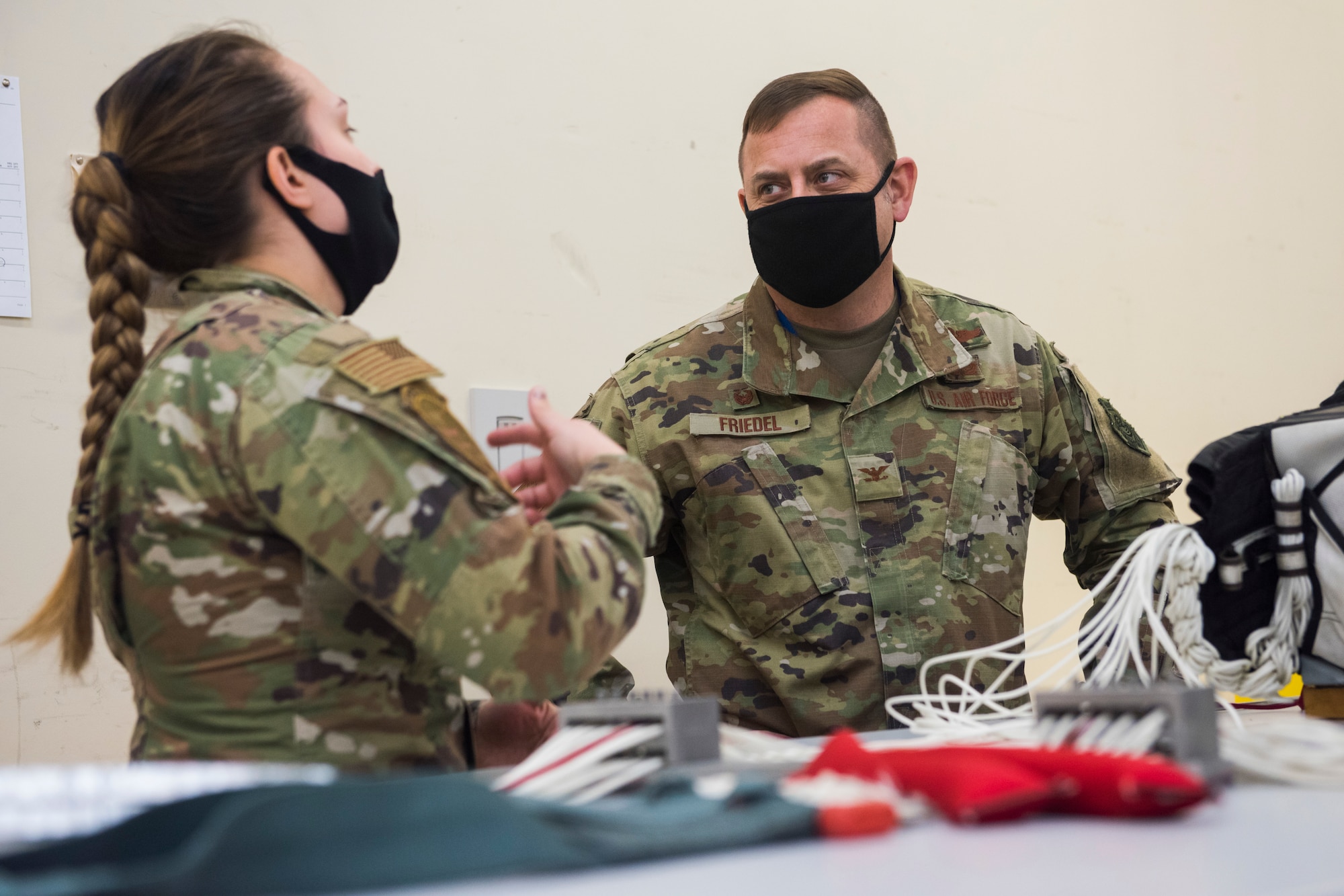 Woman and Man in uniform talk while packing a parachute.