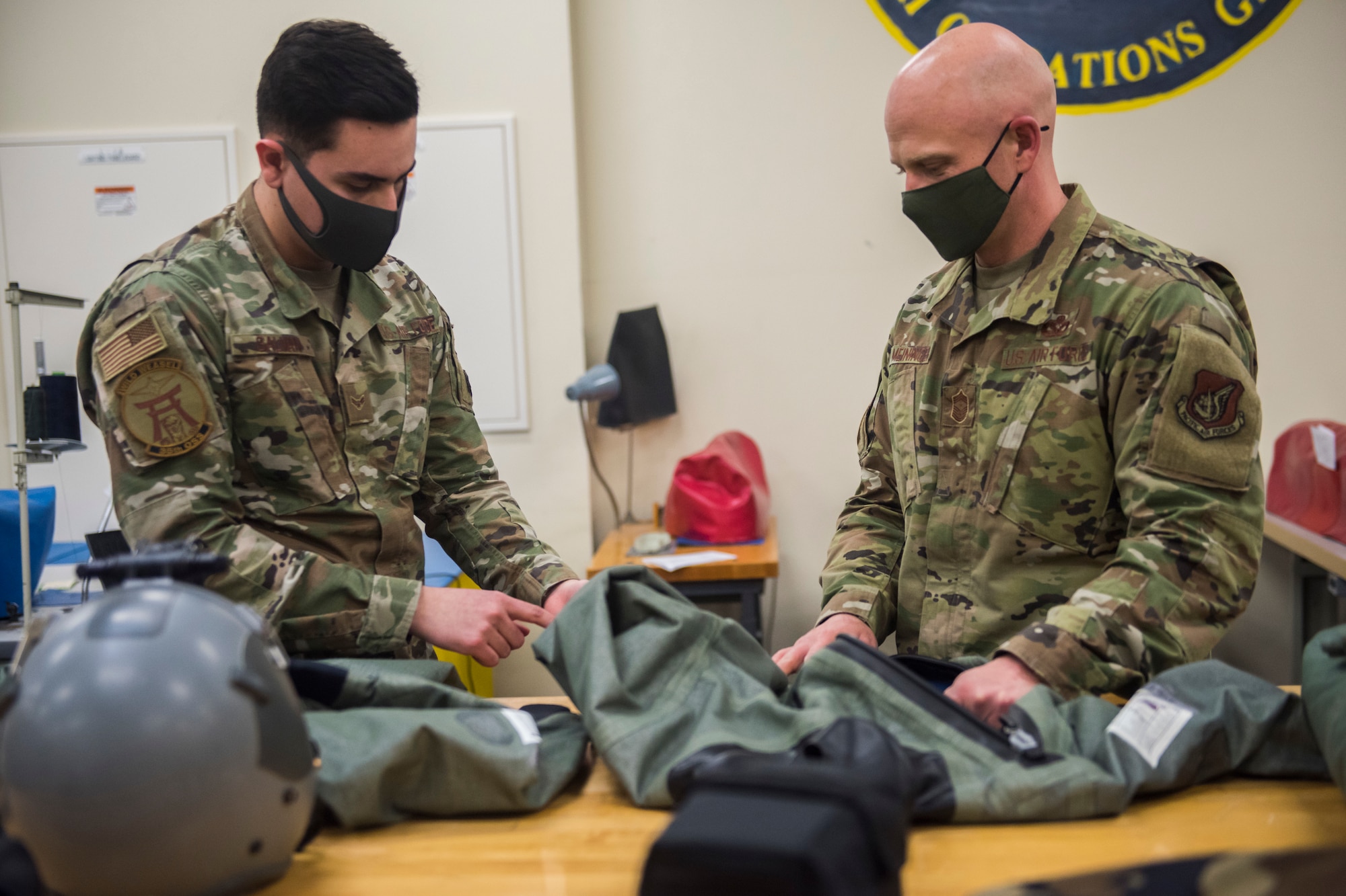 Two men in uniform talk, while looking at a waterproof suit.