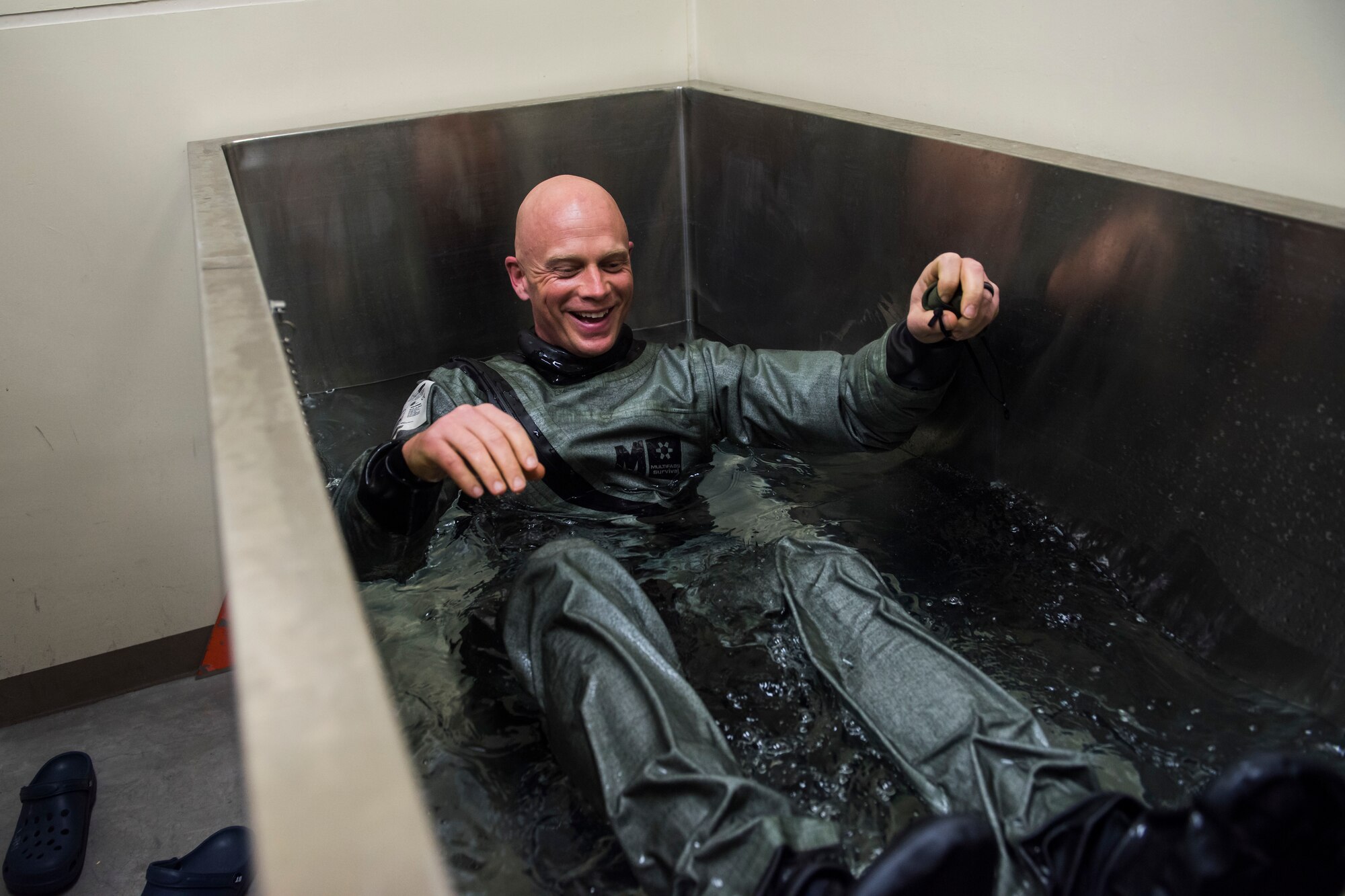 Man in waterproof suit lays in a tank of water